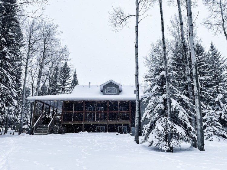 Snow falls in the backyard of a lakefront cottage
